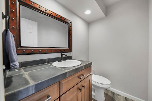 bathroom featuring toilet, hardwood / wood-style floors, and vanity