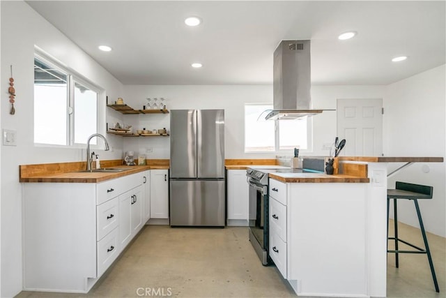 kitchen with wooden counters, appliances with stainless steel finishes, island exhaust hood, sink, and a breakfast bar area