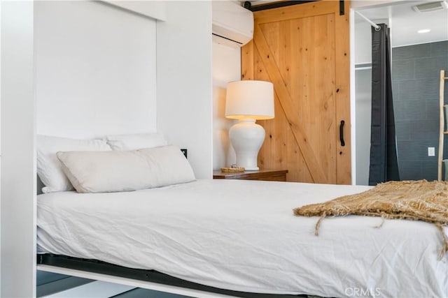 bedroom featuring a barn door, a closet, and a wall mounted air conditioner