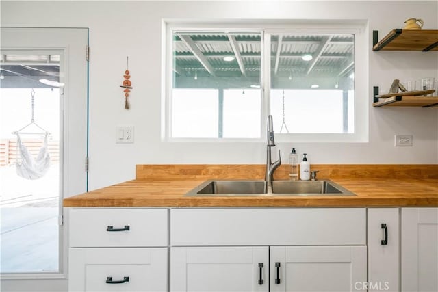 kitchen with white cabinetry, sink, and wooden counters