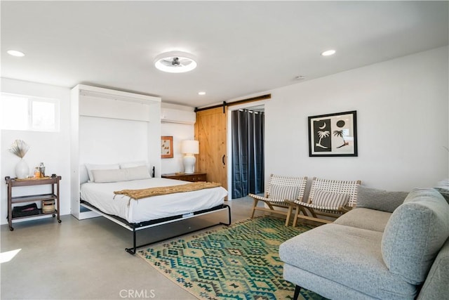 bedroom featuring concrete flooring, a barn door, and a wall mounted air conditioner