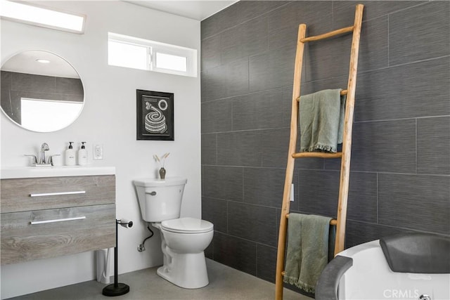 bathroom with a tub to relax in, vanity, and toilet