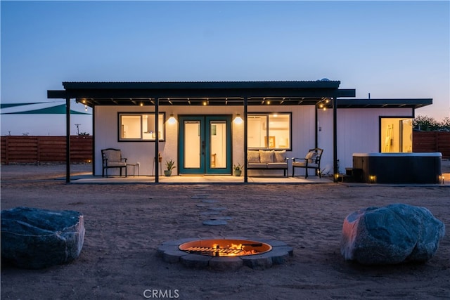 back house at dusk featuring a fire pit, a patio area, and french doors