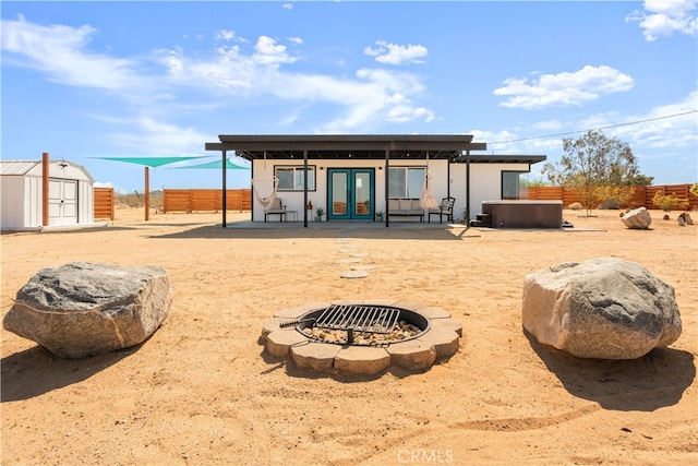 rear view of property with french doors, a storage unit, and an outdoor fire pit