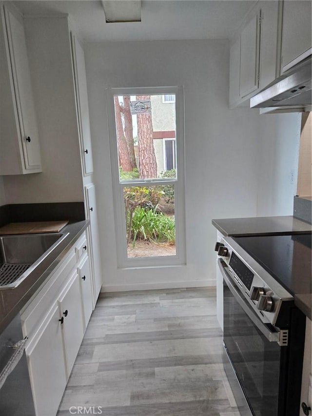1030 W Macarthur Blvd Unit 83, Santa Ana, CA 92707 - kitchen featuring appliances with stainless steel finishes, white cabinets, light wood-style flooring, dark countertops, and under cabinet range hood