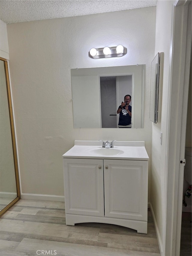 bathroom with vanity, wood-type flooring, and a textured ceiling