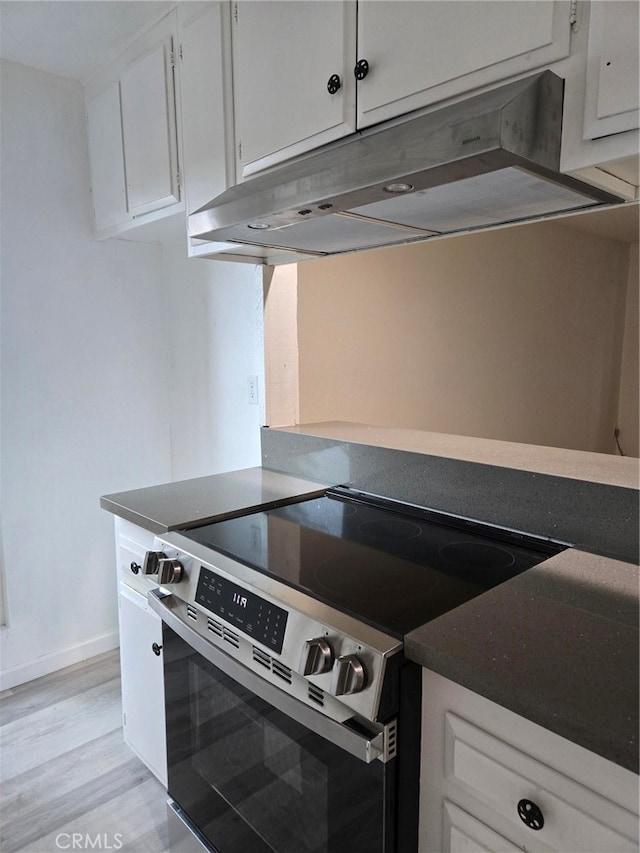 kitchen with stainless steel electric stove, white cabinets, and light wood-type flooring