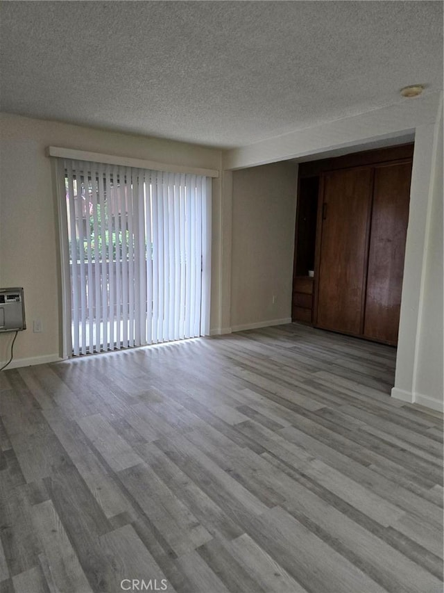 1030 W Macarthur Blvd Unit 83, Santa Ana, CA 92707 - unfurnished living room featuring a textured ceiling, wood finished floors, and a wall mounted air conditioner