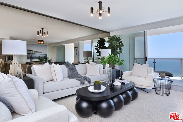 living room featuring a wealth of natural light, a water view, and a chandelier