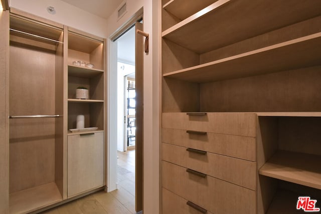 walk in closet with light hardwood / wood-style flooring