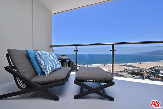 balcony with a water view and a view of the beach