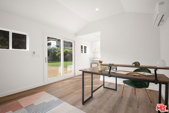 office area featuring a wall unit AC, vaulted ceiling, and light wood-type flooring