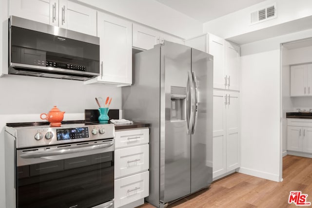 kitchen with white cabinetry, stainless steel appliances, and light hardwood / wood-style flooring