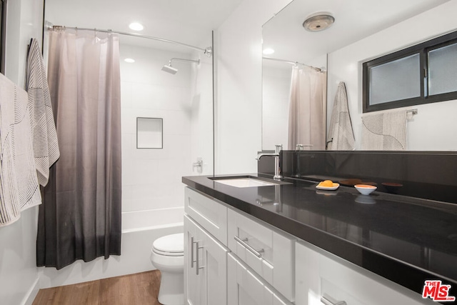 full bathroom with toilet, shower / tub combo with curtain, vanity, and hardwood / wood-style flooring