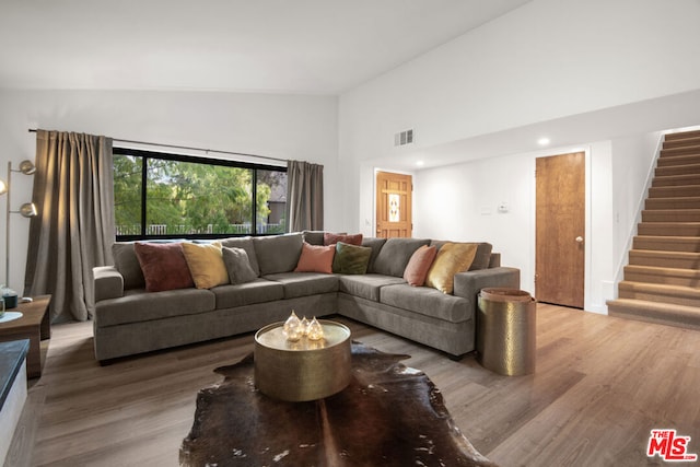 living room with hardwood / wood-style floors and high vaulted ceiling