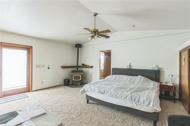 bedroom with lofted ceiling, carpet floors, a wood stove, and ceiling fan