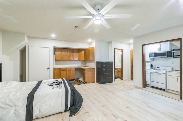 bedroom featuring ceiling fan, a textured ceiling, light hardwood / wood-style floors, and ensuite bath