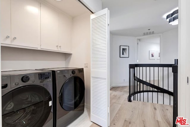 laundry room with cabinets, washer and clothes dryer, and light hardwood / wood-style floors