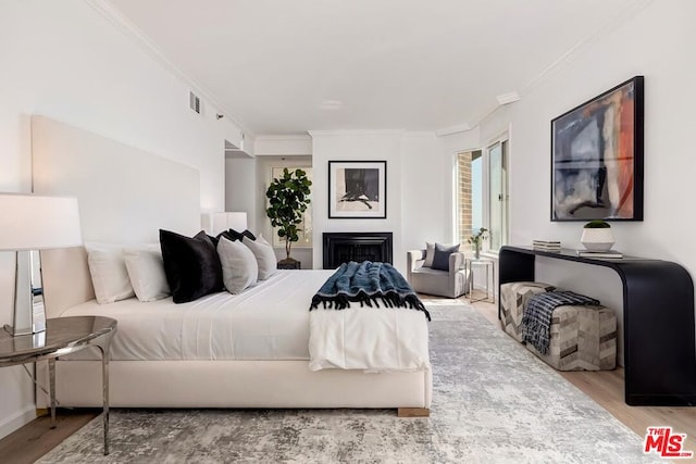 bedroom with hardwood / wood-style floors and ornamental molding