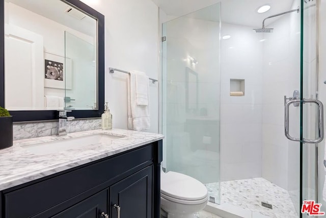 bathroom featuring vanity, toilet, and a shower with shower door