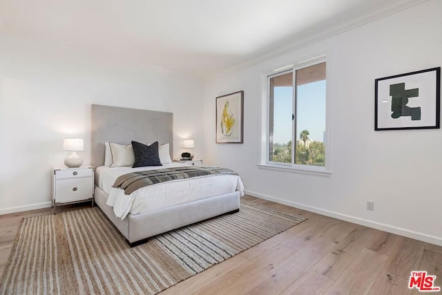 bedroom featuring ornamental molding and light hardwood / wood-style flooring