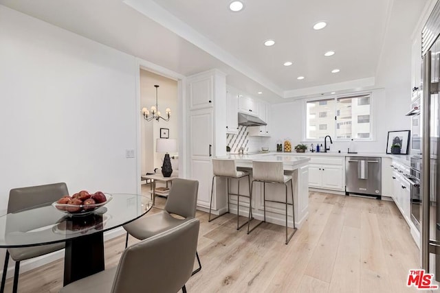 kitchen featuring dishwasher, a healthy amount of sunlight, white cabinetry, and hanging light fixtures