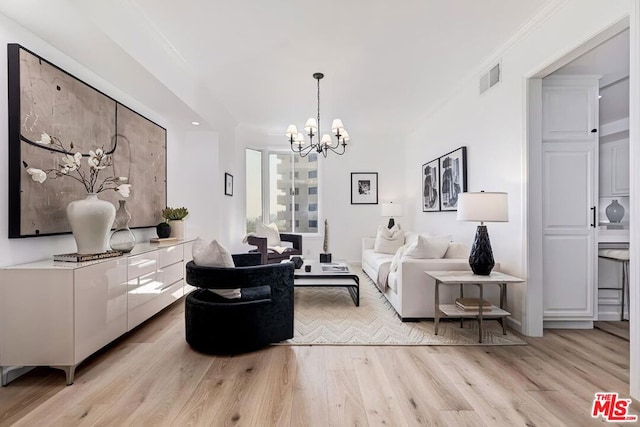 living room with ornamental molding, a notable chandelier, and light wood-type flooring