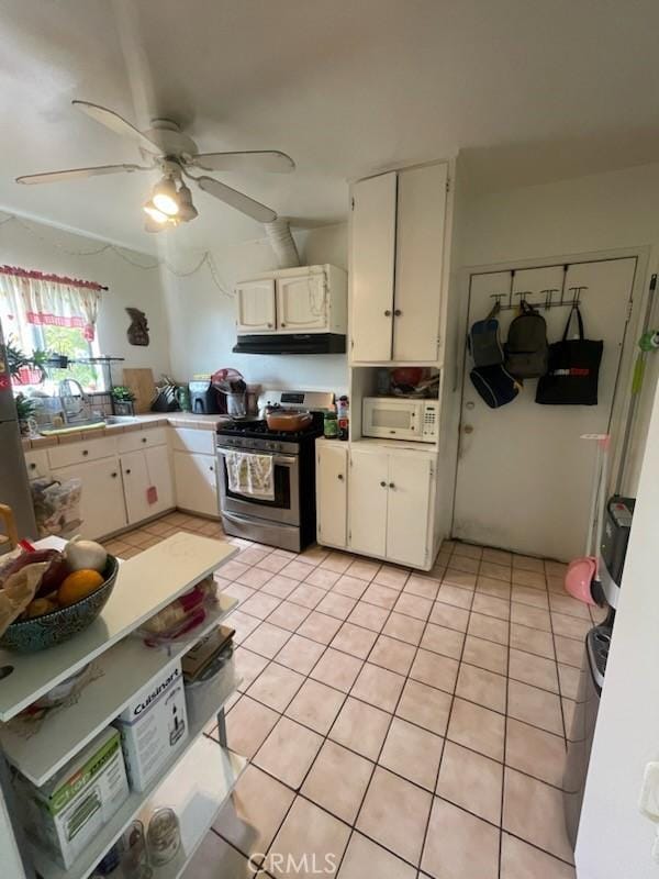 kitchen with white cabinets, light tile patterned floors, sink, and stainless steel range with gas stovetop