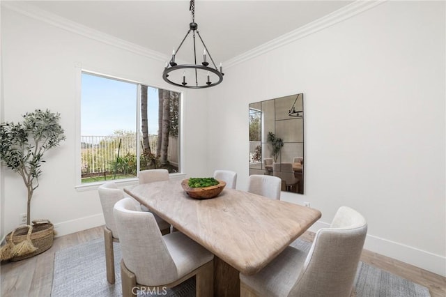 dining space featuring wood finished floors, baseboards, a notable chandelier, and ornamental molding