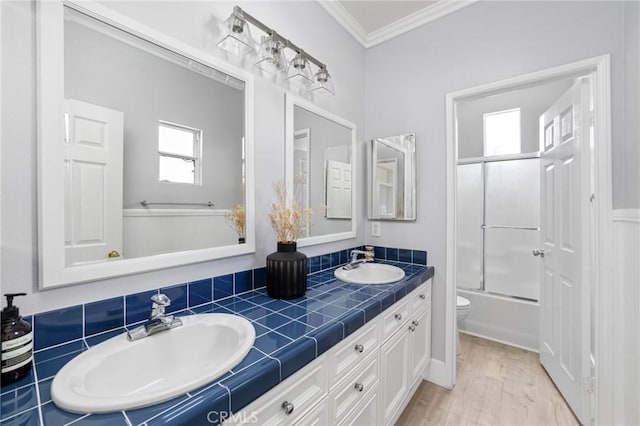 bathroom with crown molding, toilet, double vanity, and a sink