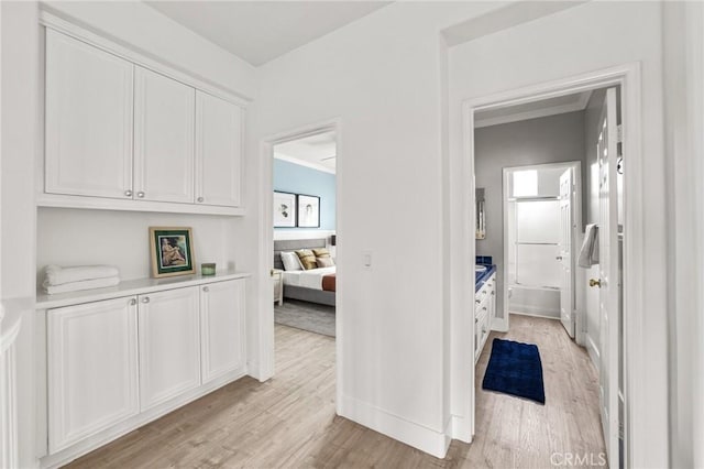 hall with baseboards, light wood-style flooring, and crown molding