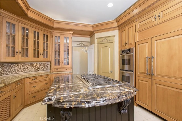 kitchen with light tile patterned floors, tasteful backsplash, dark stone counters, a kitchen island, and appliances with stainless steel finishes