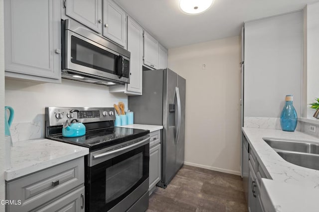 kitchen with appliances with stainless steel finishes, sink, and light stone counters