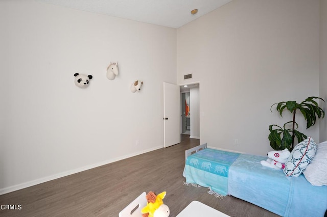 bedroom featuring a towering ceiling and dark hardwood / wood-style floors