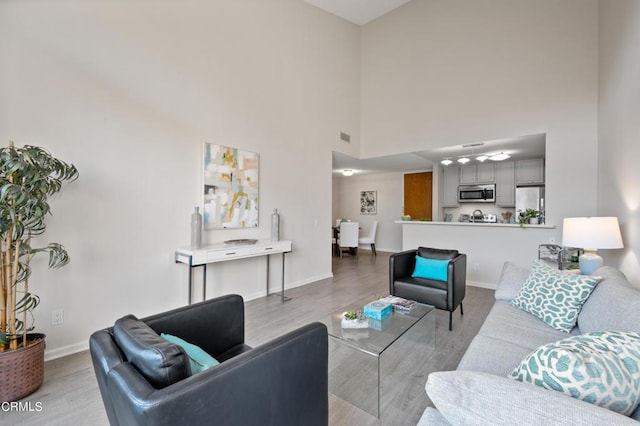 living room featuring light wood-type flooring and a high ceiling