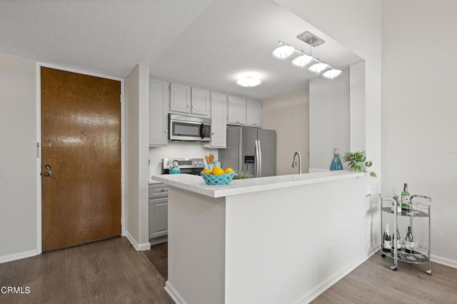 kitchen with stainless steel appliances, light hardwood / wood-style flooring, white cabinets, and kitchen peninsula