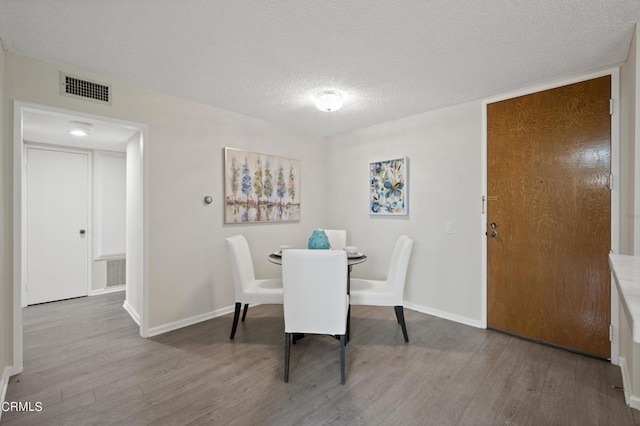 dining room with wood-type flooring and a textured ceiling