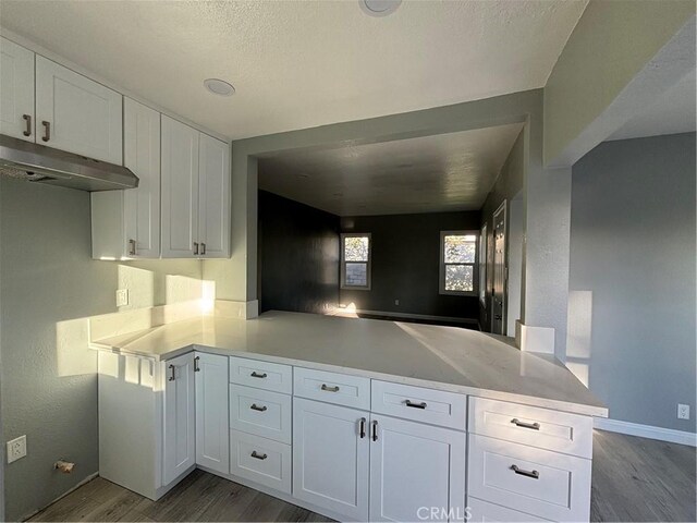 kitchen featuring kitchen peninsula, white cabinetry, and dark wood-type flooring