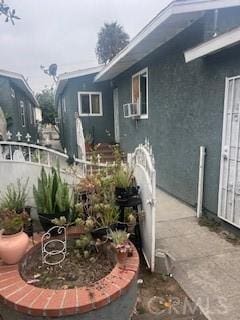 view of side of property featuring cooling unit, stucco siding, and fence