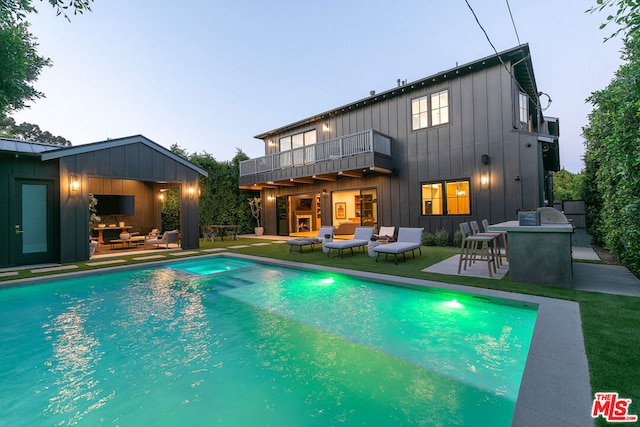 rear view of house with an outdoor living space with a fireplace, a balcony, and a patio area