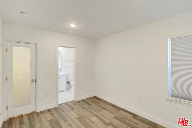 unfurnished bedroom with light hardwood / wood-style floors and ensuite bath