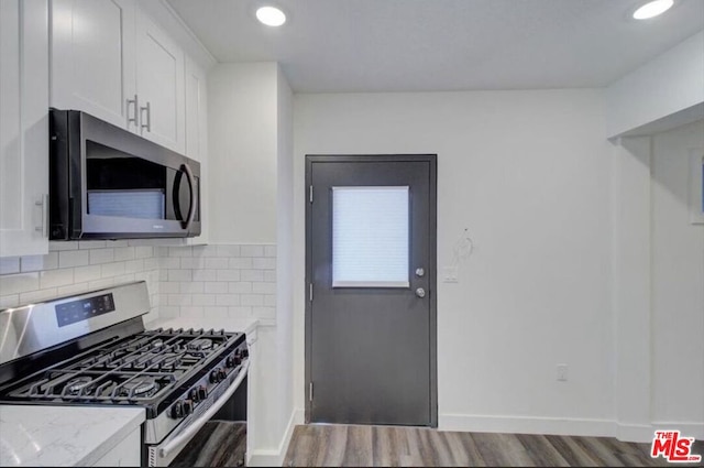 kitchen featuring tasteful backsplash, light stone countertops, appliances with stainless steel finishes, white cabinetry, and dark hardwood / wood-style floors