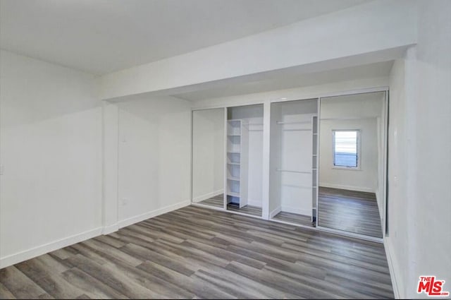 unfurnished bedroom featuring wood-type flooring and two closets