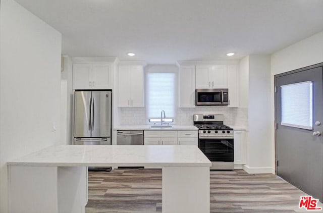 kitchen featuring sink, a kitchen breakfast bar, white cabinetry, light hardwood / wood-style floors, and stainless steel appliances