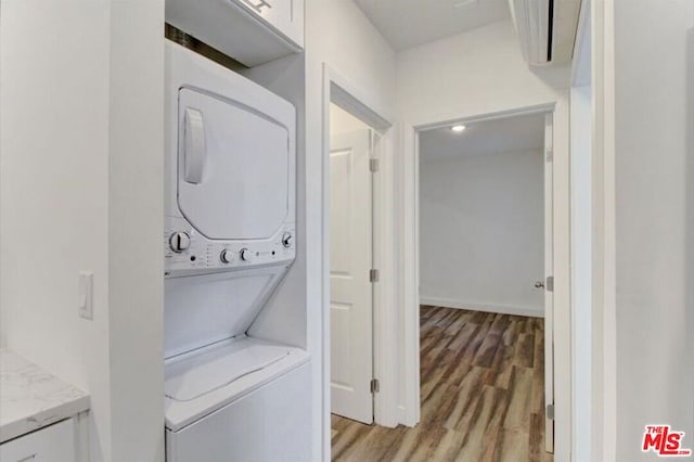 laundry area with light hardwood / wood-style floors and stacked washer and dryer