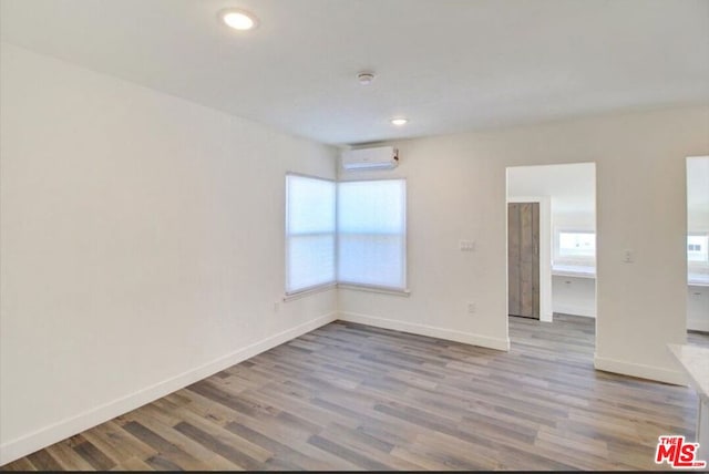 empty room with a wall mounted air conditioner and light hardwood / wood-style flooring