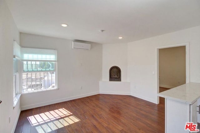 unfurnished living room with a wealth of natural light, a wall mounted air conditioner, and dark hardwood / wood-style floors