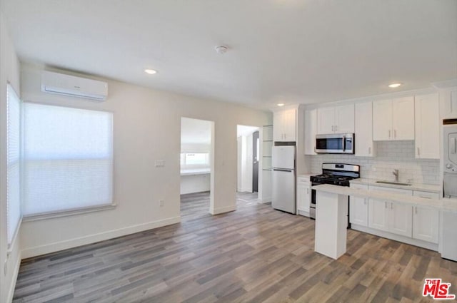 kitchen featuring an AC wall unit, appliances with stainless steel finishes, and white cabinets