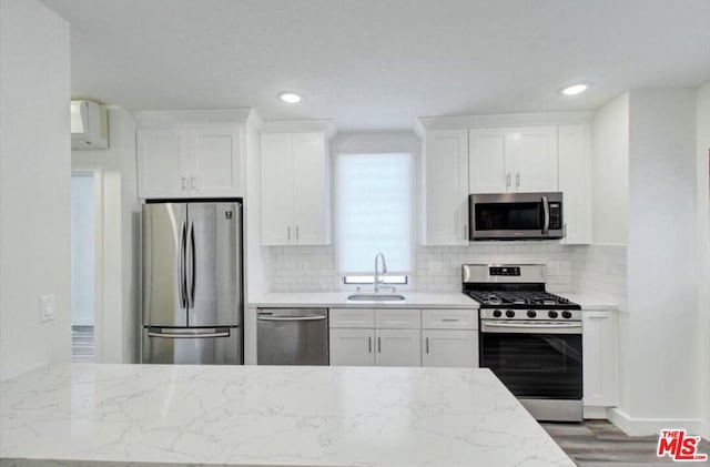 kitchen featuring white cabinets, light stone counters, dark hardwood / wood-style flooring, appliances with stainless steel finishes, and sink