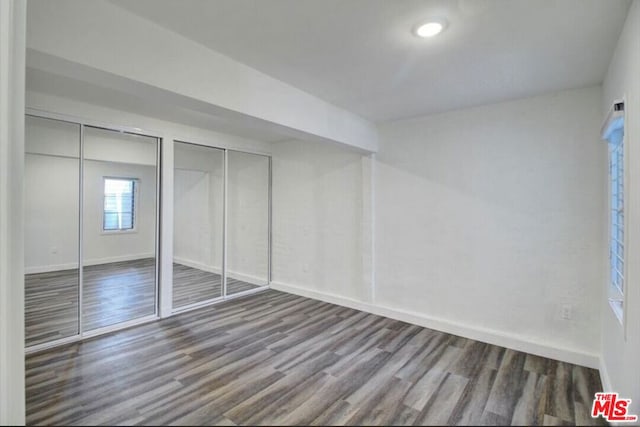 unfurnished bedroom with two closets and dark wood-type flooring